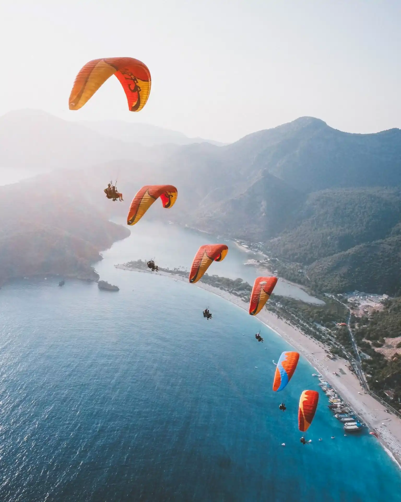 Six paragliders flying in perfect formation, side by side, showcasing precision and teamwork in the skies